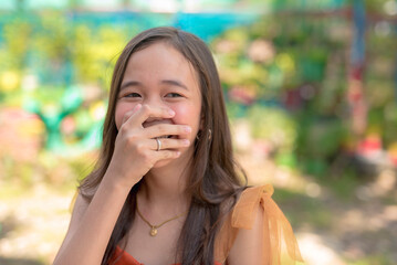 A young Asian lady covers her mouth as she laughs at the funny joke of her friend.