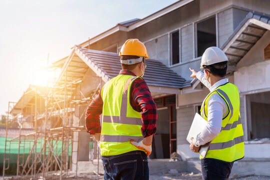 Architect and engineer construction watching unfinished house at outdoors construction site. Building construction collaboration concept. Teamwork