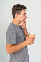Young caucasian man with a cup of coffee thinking on a white background