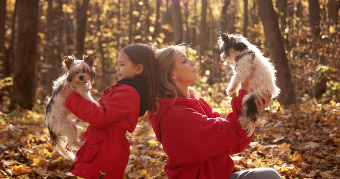 Mother and daughter playing with dogs in the forest