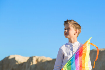 A boy with a kite stands mountain and looks into the distance. The concept of freedom and fantasy.