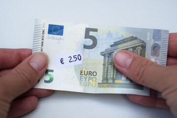 Five euro banknote with 2 euro 5 cent price tag. Selective focus on label. Inflation in Europe,...