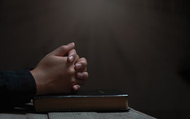 praying hands, young woman prayer with hands together over a Holy Bible on wooden table., spiritual...