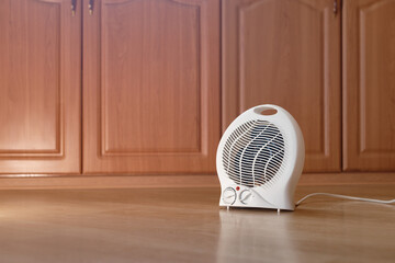 Modern electric fan heater on the floor in the room, space for text. Portable heater. Autumn...