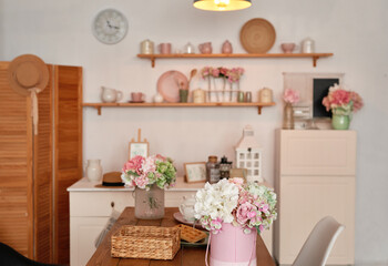 White kitchen interior in loft style. Shelves with pink crockery and kitchen utensils. Studio apartment. Rent and delivery of housing. Hostel and hotel