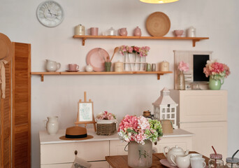 Fototapeta na wymiar White kitchen interior in loft style. Shelves with pink crockery and kitchen utensils. Studio apartment. Rent and delivery of housing. Hostel and hotel