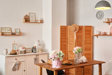 White kitchen interior in loft style. Shelves with pink crockery and kitchen utensils. Studio apartment. Rent and delivery of housing. Hostel and hotel