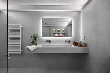 interior view of a modern bathroom covered in grey resin, in the foreground is the built-in...