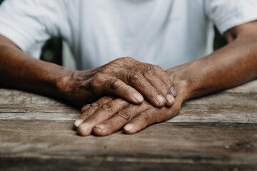 Hands of an old man on the wood table .vintage tone.