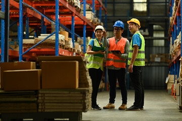 Senior male manager and young workers checking quantity of storage product while standing aisle between rows of tall shelves full of packed boxes