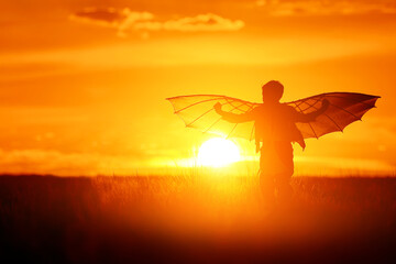 Child silhouette with wings at sunset. Funny kid run in the meadow on a summer evening. Boy dream of flying and imagine themselves as pilots. - 528000312