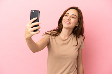 Young caucasian woman isolated on pink background making a selfie