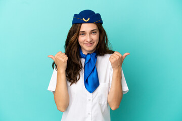 Airplane stewardess woman isolated on blue background with thumbs up gesture and smiling