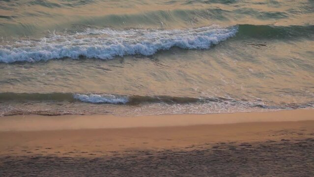 High angle slow motion shot of sea waves at Cabo De Rama Beach during the sunset as seen from a cliff besides the beach at South Goa in India. View of the sea waves during the sunset on a clean beach.