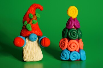 A toy gnome with a Christmas tree on a green background. New Year and Christmas. Fabulous scenery.