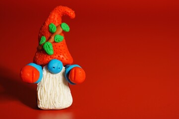 A toy gnome on a red background. New Year and Christmas. Fabulous scenery.