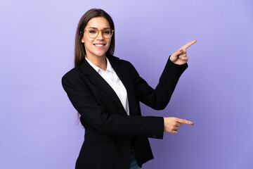 Business woman isolated on purple background pointing finger to the side and presenting a product