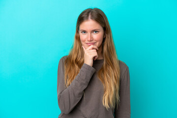 Young blonde woman isolated on blue background thinking