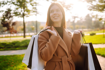 Beautiful woman with shopping bags walking on street. Autumn shopping. Purchases, black friday, discounts, sale concept.