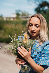 Beautiful girl holding wildflowers and duckling in her hands