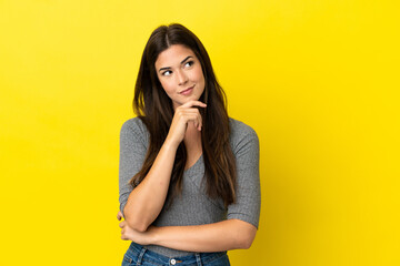 Young Brazilian woman isolated on yellow background and looking up