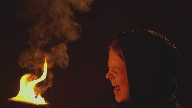 girl in a black sweatshirt holding a bowl of fire and screaming