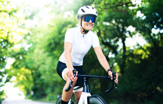 Rennradfahrer, sportliche Frau in Fahrradkleidung und mit Helm beim Sport