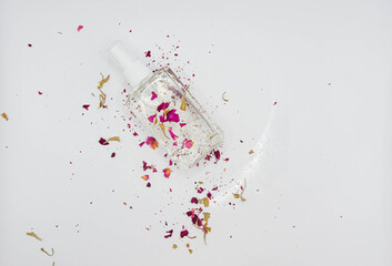 Flat lay composition with bottle of perfume and petals on white marble background, space for text