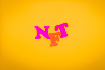 Non fungible token. NFT acronym of multicolored letters on yellow background. Crypto Art concept. Copy space