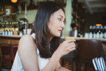 Beautiful asian woman sittinf vintage cafe drinking hot coffee