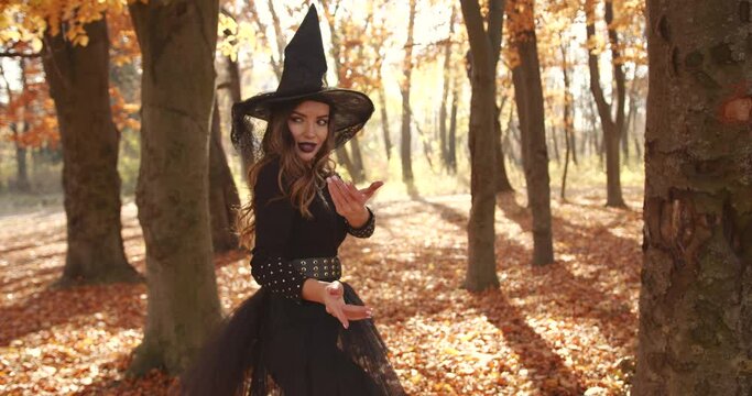 Attractive woman in a special dress and hat looks like a witch in the autumn forest