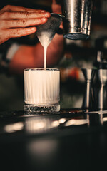 man hand bartender making white cocktail in glass on the bar counter