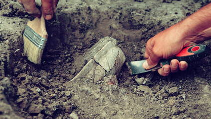 Archaeological excavations, archaeologists work, dig up an ancient clay artifact with special tools © Mariana Rusanovschi