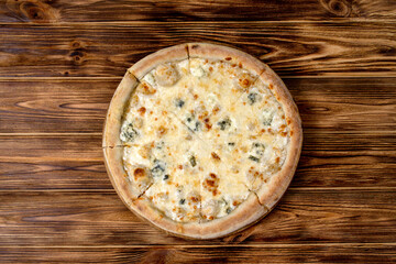 Pizza with four cheeses, mozzarella, blue cheese, Parmesan cheese. Italian cuisine. On a wooden background. View from above.