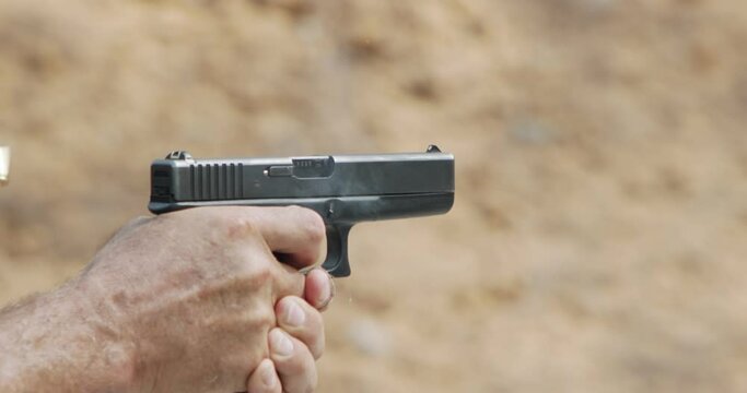 Slow motion of a hand gun firing in a firing range with cartridge flying away