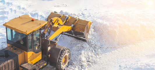 A large orange tractor removes snow from the road and clears the sidewalk. Cleaning and clearing...
