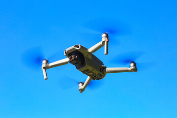 Small high tech drone flying in front of blue sky