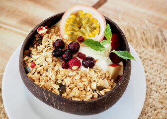 muesli,mixed fruit yogurt with granola on coconut bowl