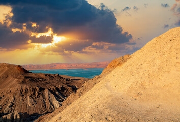 Sunset on a large salt formation mountains range Sodom with fluffy clouds. Sun shining on rocky...