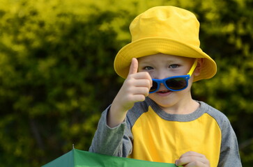 Positive boy in a yellow panama hat and sunglasses. Child 5 years old. The boy rejoices in the journey, going to the atrankion park, preparing for school. Emotions on the face. Resort for children, su
