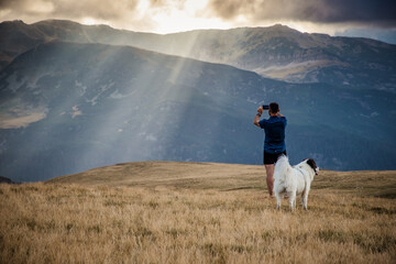 Obraz premium man and dog trekking in high mountains