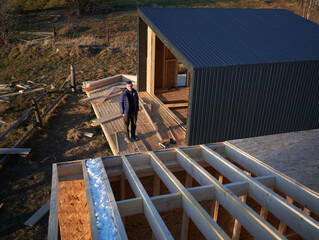Male architect building wooden frame house in the Scandinavian style barnhouse. Man standing on...