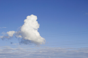 fluffy white cloud in blue sky with wires