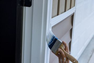 Paintbrush are used by a contractor painter to paint wooden moldings on door trims