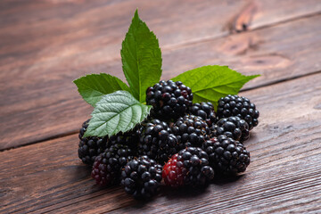 Blackberries with leaves on wooden background close up