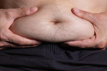 Fat man holding excessive fat belly, overweight fatty belly isolated grey background.