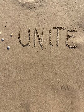 on the beach is carved with letters in the smooth sand the writing unite