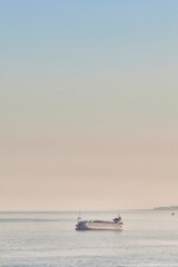 Transport boat sailing through the sea during sunset, off the coast of Malaga moving away from the city