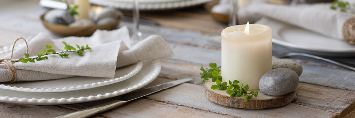 Rustic zero waste wedding decor with natural elements. Wooden table, candles, linen napkins, branches with green leaves. Eco-friendly decoration for the special dinner. Romantic and cozy place. Banner