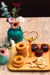 Rosquinhas na mesa com outros doces, jarro de flores e café